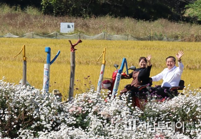 지난 17일 가사문학면 청촌마을 경로잔치에 참석한 이병노 담양군수가 어르신들이 가꾼 꽃길을 마을부녀회장과 함께 전동스쿠터를 타고 돌아보고 있다.